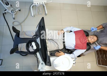 Photo en longueur d'un patient de sexe masculin dans une chaise de dentiste Banque D'Images