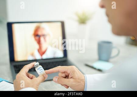 Un médecin de sexe masculin est titulaire du vaccin contre le coronavirus et utilise un ordinateur portable en clinique Banque D'Images