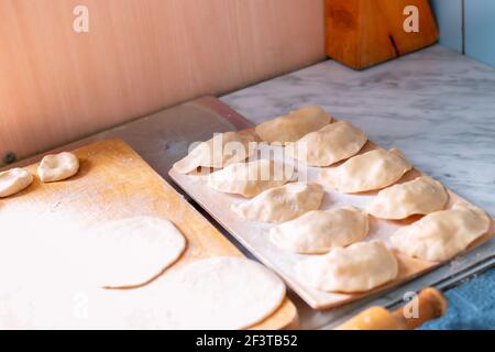 Cuire des boulettes avec des pommes de terre, sur une planche de bois une préparation de pâte, sur une autre planche un produit fini, cuisine russe Banque D'Images