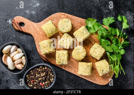 Billes de falafel brutes sur une planche à découper en bois. Arrière-plan noir. Vue de dessus Banque D'Images