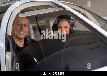 Portrait d'une jeune femme attirante pilote stagiaire avec un casque se préparant à voler. Elle est assise à côté de l'instructeur et regarde la caméra. Banque D'Images