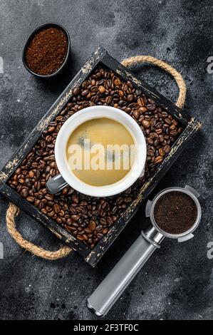 Tasse de café et haricots dans un ancien plateau en bois fond noir. Vue de dessus Banque D'Images