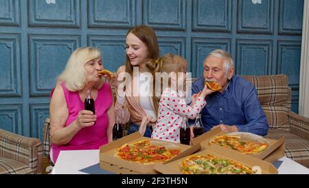 Famille ayant la fête du déjeuner, se nourrir les uns les autres avec de la pizza, rire, en appréciant le repas ensemble à la maison Banque D'Images