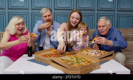 Famille multigénérationnelle ayant la fête du déjeuner, manger de la pizza, rire appréciant le repas ensemble Banque D'Images