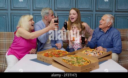 Bonne famille multigénérationnelle, déjeuner à la maison, manger de la pizza, élever des toasts ensemble Banque D'Images