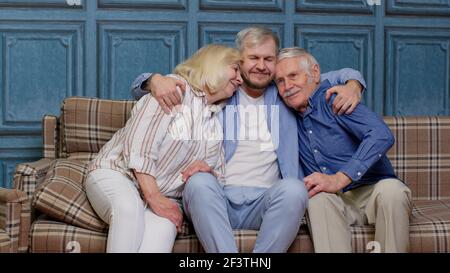 Famille de grands-parents âgés avec un fils adulte qui se moque de s'amuser en regardant le collage des caméras à la maison Banque D'Images