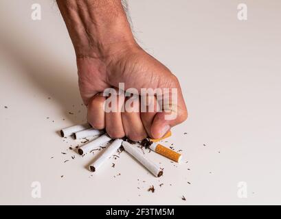 Poing d'un homme frappant une pile de cigarettes cassées sur une table blanche, comme signe de désapprobation et de rejet du tabac. 31 mai, journée internationale sans Banque D'Images