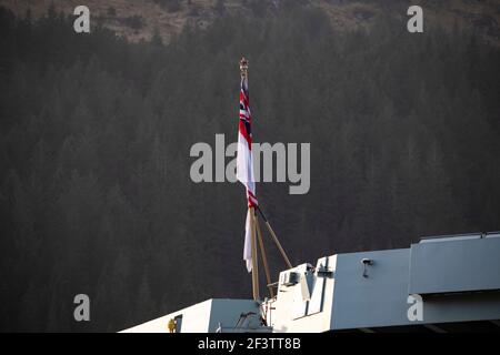 Finnart, Loch long, Écosse, Royaume-Uni. 17 mars 2021. Drapeau de croix Saint-Georges. Le HMS Queen Elizabeth est le navire de guerre le plus grand et le plus avancé jamais construit pour la Marine royale. Le HMS Queen Elizabeth (en photo) et le HMS Prince of Wales sont les navires-drapeaux du pays qui pèsent 65,000 tonnes et mesurent 280 mètres de longueur. Le porte-avions est actuellement amarré sur le côté de long Loch à Glen Mallan pour prendre du carburant, des munitions et d'autres fournitures, avant les exercices navals qui font partie du groupe d'attaque britannique Carrier Strike Group 2021. Le bateau doit partir le dimanche. Crédit : Colin Fisher/Alay Live News Banque D'Images