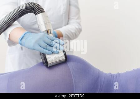 L'esthéticienne fait le massage GPL de la boté d'une jeune femme en costume violet. Massage du drainage lymphatique. Traitements amincissants. Banque D'Images