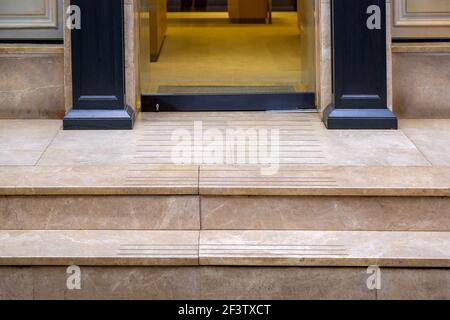 seuil en marbre beige avec marches à l'entrée de la porte en verre d'un magasin cher avec bois décoratif noir colonnes sur la façade du bu Banque D'Images