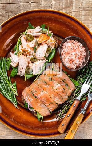 Bruschetta au saumon fumé chaud et froid, arugula, câpres sur une assiette rustique aux herbes. fond en bois. Vue de dessus Banque D'Images