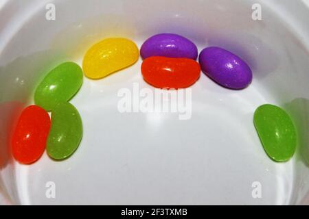 Huit jellybeans dans le fond d'un plat blanc Banque D'Images