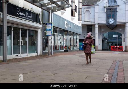 Carmarthenshire, Royaume-Uni. 17 mars 2021. Une femme portant un masque comme mesure préventive contre la propagation du covid-19 porte des sacs d'achats tout en marchant le long d'une rue dans le sud du pays de Galles, au Royaume-Uni.huit personnes de plus sont mortes avec le coronavirus au pays de Galles et le taux d'infection global a légèrement augmenté. Crédit : SOPA Images Limited/Alamy Live News Banque D'Images