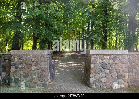 L'entrée des portes dans le parc vert, qui ont été faites de pierres de granit brun, de à la porte se déplace immédiatement de l'allée ombragée sortant en perspective avec Banque D'Images