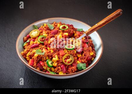 Chili con carne avec une cuillère sur fond noir Banque D'Images