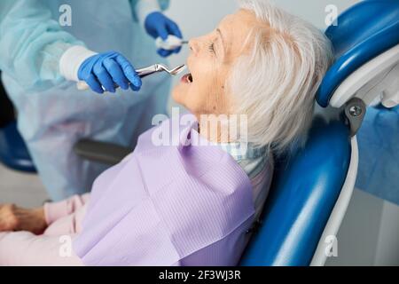 Dentiste travailleur de clinique fournissant l'extraction du forcep de la dent du patient Banque D'Images