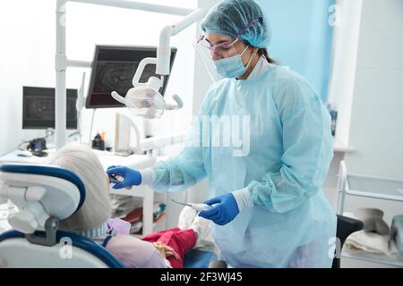 Femme chirurgien dentaire effectuant une extraction dentaire sur le patient Banque D'Images
