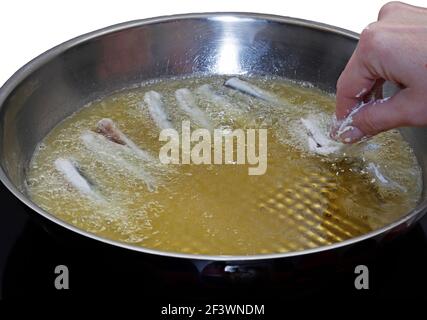 Main d'une femme mettant des anchois dans une poêle Banque D'Images