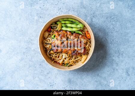 Retirez le poulet japonais Yakitori avec les haricots Noodle et Edamame dans un bol en plastique à emporter. Prêt à manger. Banque D'Images