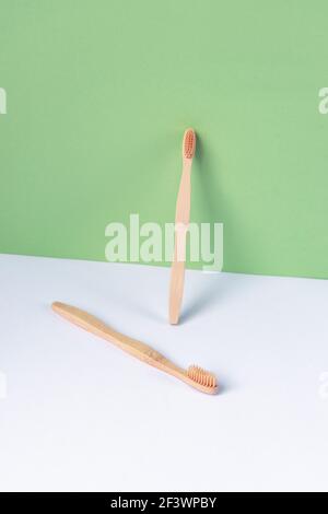 Deux brosses à dents sur une table blanche contre un mur vert. Concept d'hygiène personnelle et d'auto-soins. Banque D'Images