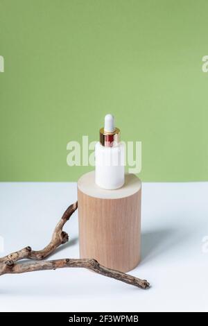 Huile essentielle naturelle ou sérum en bouteille blanche sur un podium en bois. Médecine alternative, produit de soins de beauté pour la peau. Copier l'espace. Backgro blanc et vert Banque D'Images