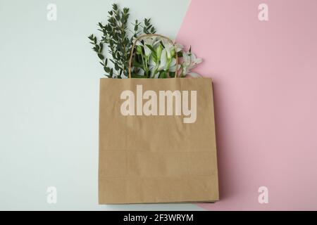 Sac en papier avec des fleurs sur un fond bicolore, un mockup de shopping style printemps Black Friday avec espace de texte Banque D'Images