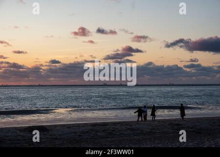 Vue sur les silhouettes des personnes marchant dans le soleil couchant sur la mer et réfléchi sur la plage, nuages avec des bords brillants de soleil. Paysage. Photo de haute qualité montrant le concept de liberté et de rêves Banque D'Images