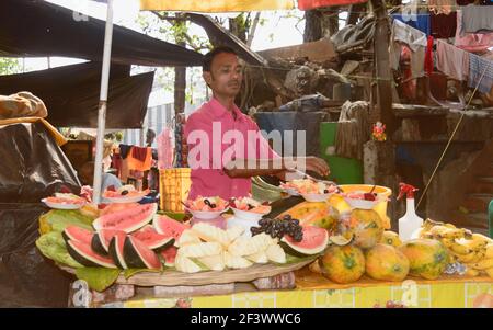 Un homme qui vend des fruits frais préparés coupés en morceaux sa nourriture de rue stalle sur chariot de la cabine de fruits pendant l'été Dans la rue de Kolkata West Bengal Inde ainsi Banque D'Images