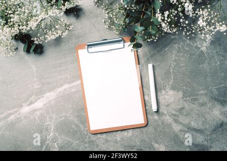 Espace de travail féminin avec carnet, presse-papiers, papier, pivoine rose, fleur d'eucalyptus sur fond de marbre. Vue de dessus, espace de copie. Blogueur, féminin Banque D'Images