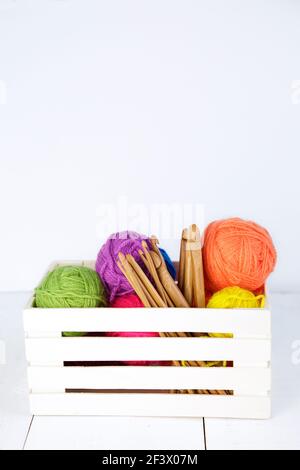 Boîte en bois avec crochets en crochet de bambou naturel et boules de laine de différentes couleurs. Copier l'espace. Banque D'Images