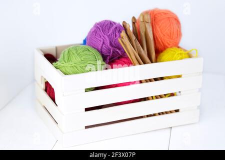 Vue de dessus d'une boîte en bois avec des crochets en bambou naturel et des boules de laine de différentes couleurs. Banque D'Images
