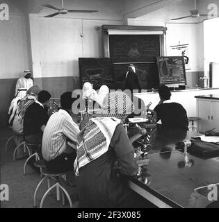 1960s, étudiants arabes historiques dans une salle de classe, avec un professeur au tableau de blackboard, Djeddah, Arabie Saoudite. Banque D'Images