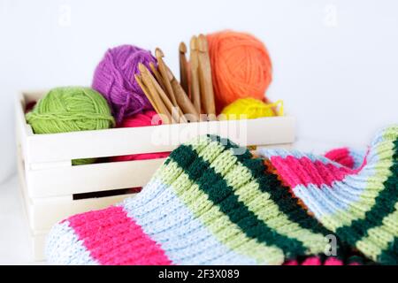 Boîte en bois avec crochets en crochet de bambou naturel et boules de laine de différentes couleurs. Banque D'Images