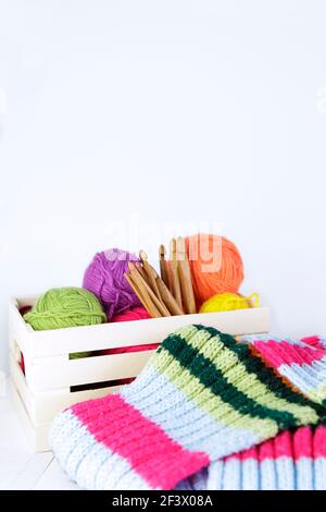 Boîte en bois avec crochets en crochet de bambou naturel et boules de laine de différentes couleurs. Copier l'espace. Banque D'Images