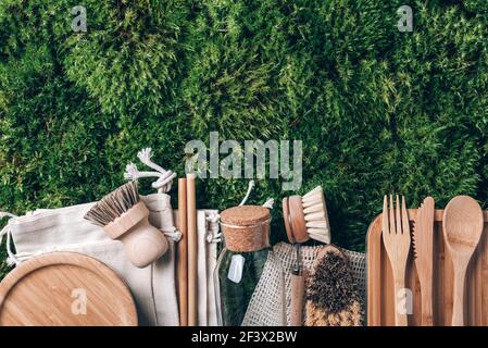 Brosses à vaisselle, sac en coton réutilisable, couverts en bambou, bol en verre, brosse de cuisine, paille sur fond de mousse verte. Vue de dessus. Copier l'espace. Durable Banque D'Images