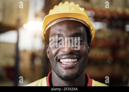 Portrait d'un ouvrier africain heureux regardant l'appareil photo à l'intérieur Magasin d'entrepôt – concentrez-vous sur le visage Banque D'Images