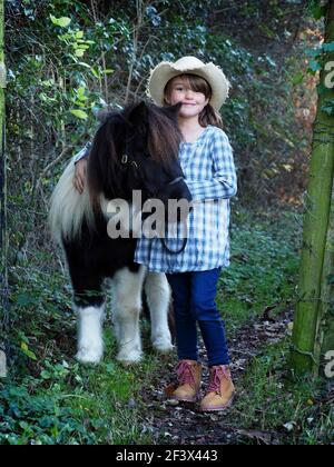 Une fille dehors avec son poney noir et blanc Banque D'Images