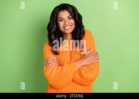 Photo de douce charmante peau sombre dame vêtue pull-over tricoté se serrer les yeux fermés isolé de couleur verte arrière-plan Banque D'Images