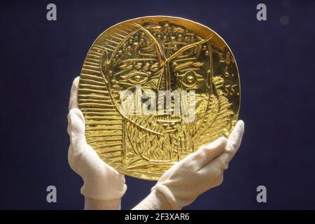 Un employé de Bonhams détient 'visage de Faune', une repoussŽ plaque d'or de 22 carats produite par Pablo Picasso et le forgeron Franois Hugo qui a une estimation de £250,000-350,000 lors d'un appel photo à Bonhams à Londres, avant leur prochaine vente de Picassomania, qui aura lieu le 23 mars. Date de la photo: Jeudi 18 mars 2021. Banque D'Images