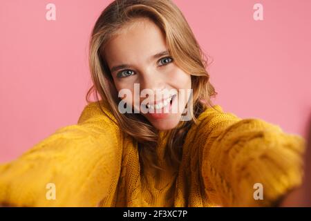 Amuse belle fille montrant sa langue tout en prenant la photo de selfie isolé sur fond rose Banque D'Images