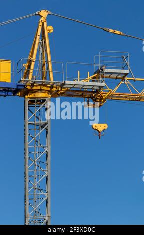 Colonne verticale et chariot à poulie pour grue à tour. Structure en acier jaune et gris contre ciel bleu. Palan pour machines ou équipements utilisés dans la construction Banque D'Images
