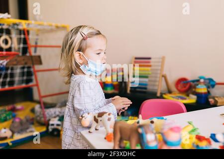 Budva, Monténégro - 17 mars 2021: Enfant fille dans un masque de protection jouant à la maternelle. Banque D'Images