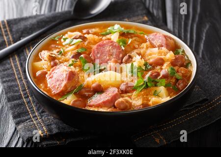 Soupe de choucroute chaude maison avec haricots borlotti, pommes de terre et saucisses dans un bol sur la table. Horizontale Banque D'Images