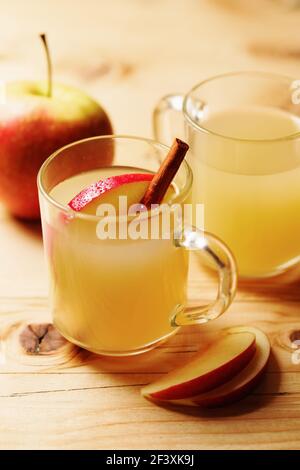 Cidre de pomme fait maison dans une tasse de verre avec cannelle et une tranche de pomme sur une table en bois Banque D'Images