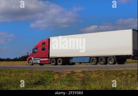 Une grande semi-remorque se déplace sur une route de campagne par une journée d'été. Banque D'Images