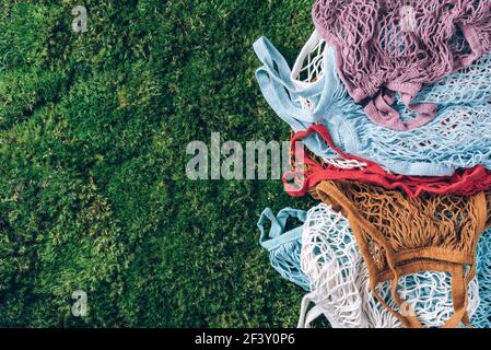 Sacs en filet réutilisables colorés ou mesh shoppers sur herbe verte, fond de mousse. Concept sans déchets, sans plastique. Vue de dessus. Cabas en maille écologique Banque D'Images