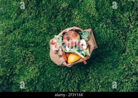 Vue de dessus. Les déchets alimentaires de la cuisine sont collectés dans un sac de papier artisanal. Légumes pelés sur l'herbe verte, fond de mousse. Durable, zéro gaspillage Banque D'Images