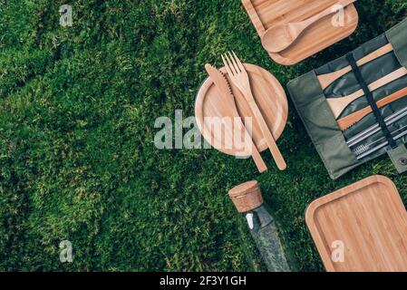 Set de couverts en bambou écologique, pots en verre, bouteille, pailles, boîtes à lunch sur herbe verte, fond de mousse. Zéro déchet, pique-nique sans plastique. Vue de dessus Banque D'Images