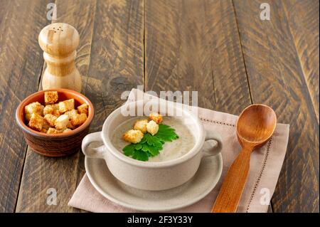 Soupe à la crème de champignons sur une table, servie avec des croûtons et du persil. Banque D'Images