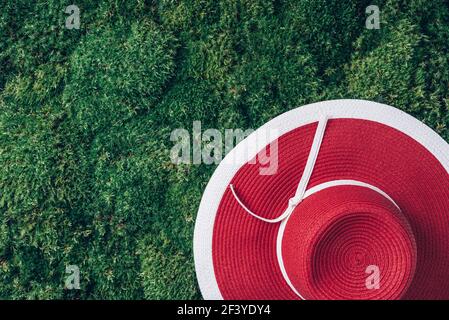 Pique-nique. Chapeau rouge d'été pour femmes sur fond de mousse d'herbe verte. Vue de dessus. Copier l'espace. Voyage d'été et concept de vacances Banque D'Images